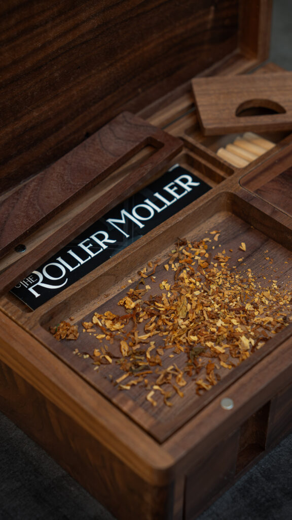 Close-up of the Compact Edition interior with dried material on the wooden tray and paper accessories in compartments.